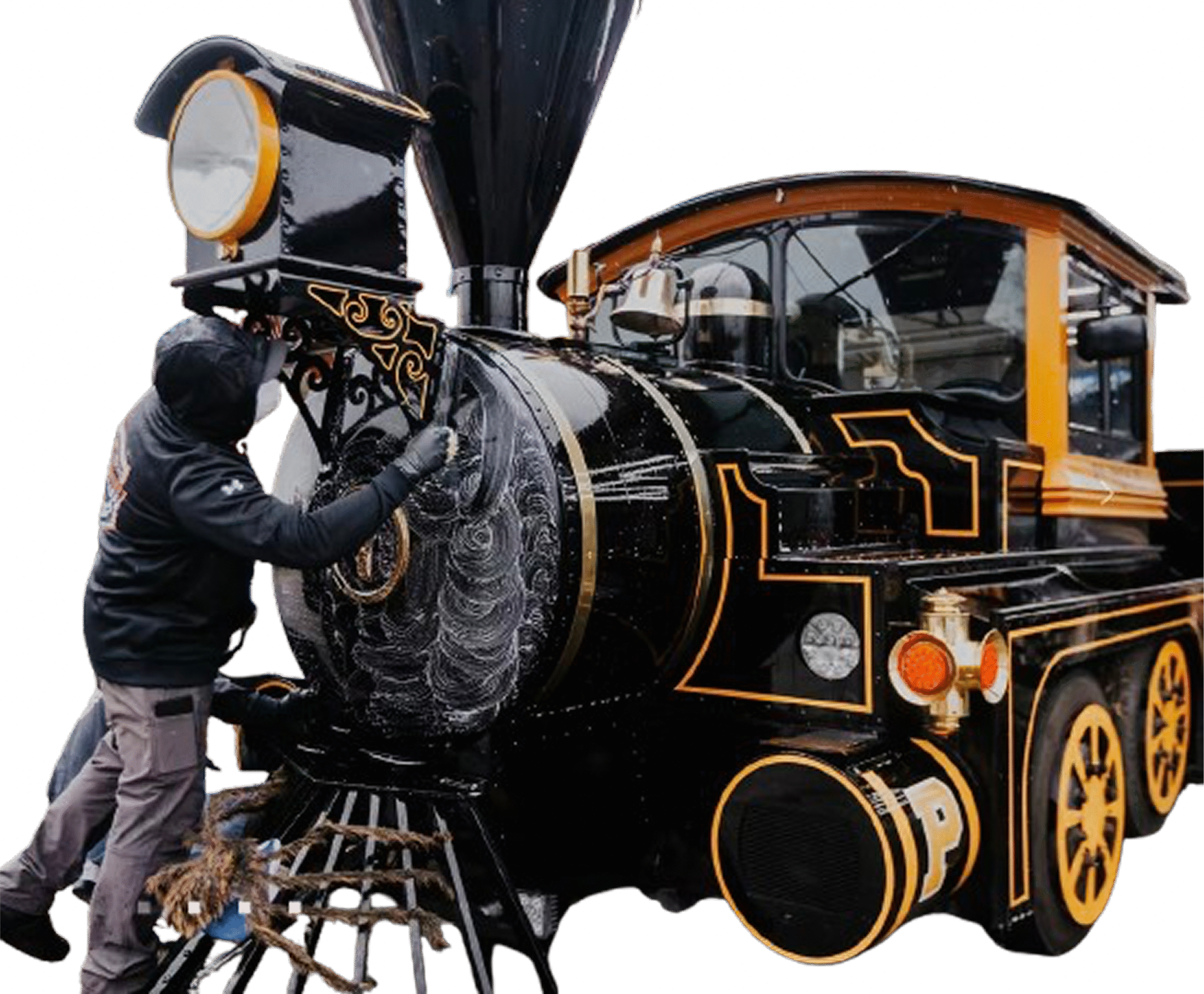 A detailer cleaning and polishing the front of a vintage black and gold train engine using foam during a restoration detailing session.