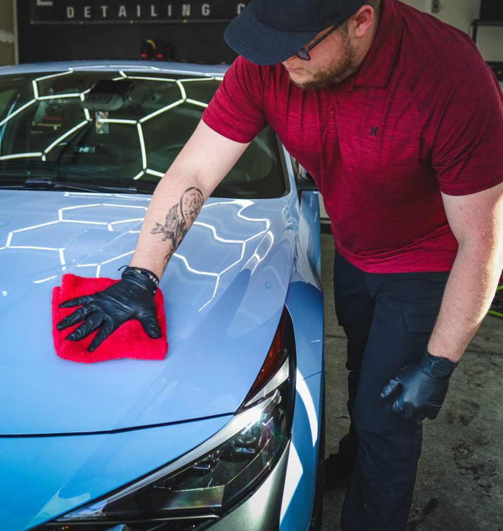A detailer applying product to the roof of a car inside the Gray Market Detailing Co. garage.